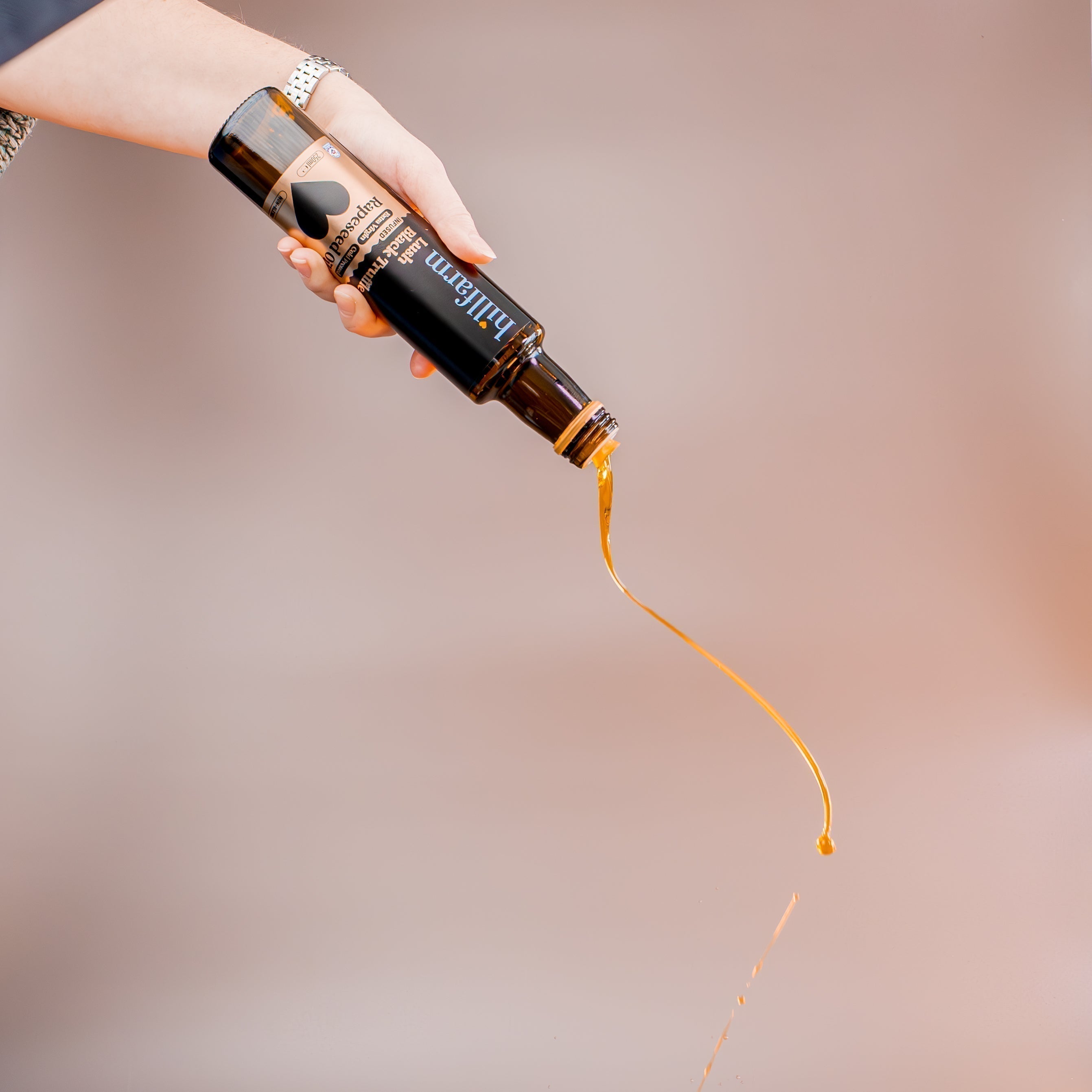 Hillfarm cold-pressed premium rapeseed oil being drizzled out of the bottle